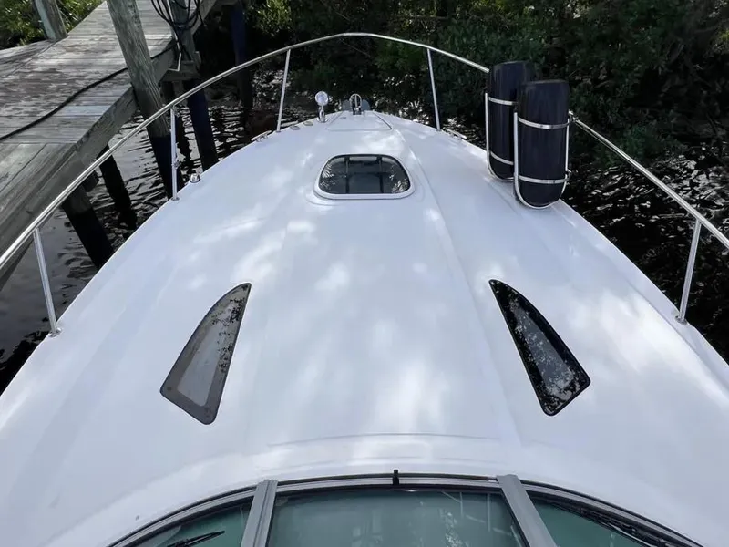 Slide: The Image of 2015 Sea Ray 330 Sundancer boat deck with sleek design and dock view. - 14