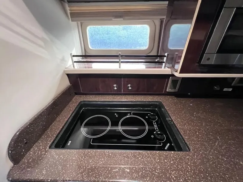 Slide: The Image of 2015 Sea Ray 330 Sundancer kitchen with stovetop and window view. - 18