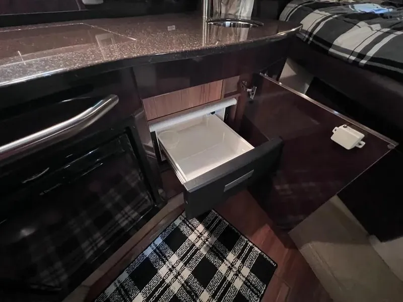 Slide: The Image of 2015 Sea Ray 330 Sundancer interior with open cabinet and drawer, featuring modern design. - 19