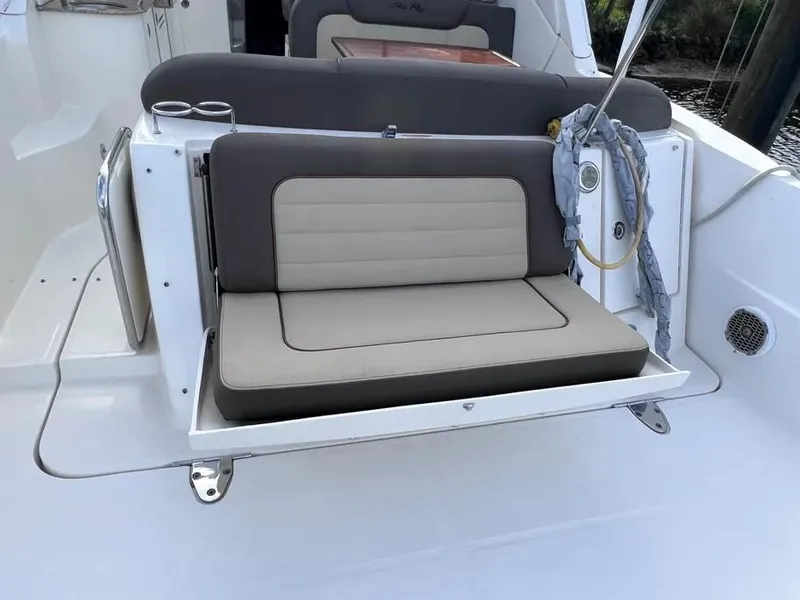 Slide: The Image of 2015 Sea Ray 330 Sundancer boat seating area with cushioned bench and cup holders. - 3