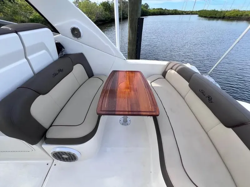 Slide: The Image of 2015 Sea Ray 330 Sundancer interior with elegant seating and wooden table by the water. - 7
