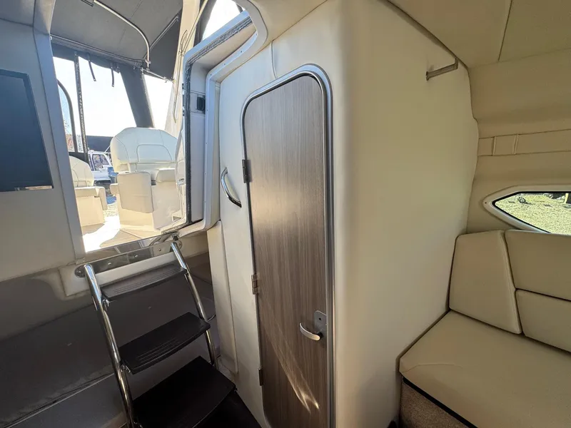 Slide: The Image of Interior of 2019 Regal 26 XO boat, featuring cabin seating and a wooden door. - 34