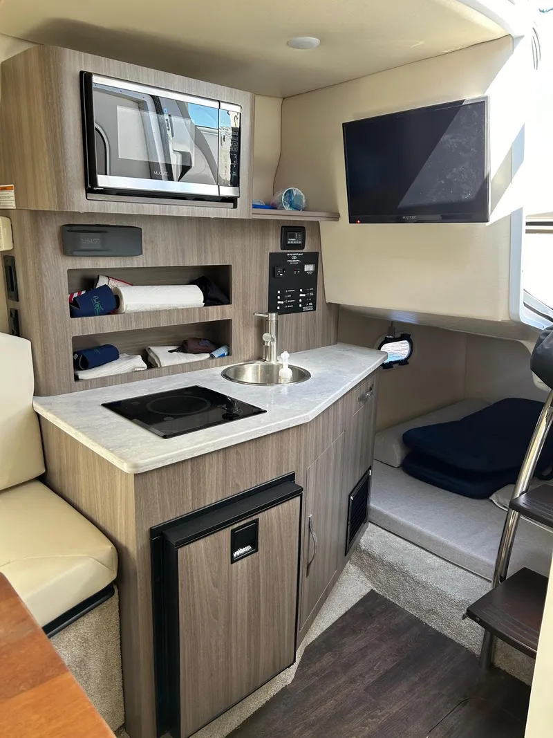 Slide: The Image of 2019 Regal 26 XO boat interior with kitchenette, microwave, sink, and TV. - 38