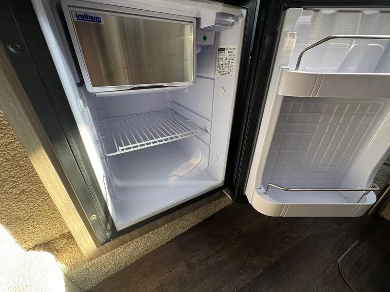 Slide: The Image of Open mini fridge inside 2019 Regal 26 XO boat, showing empty shelves and door storage. - 39
