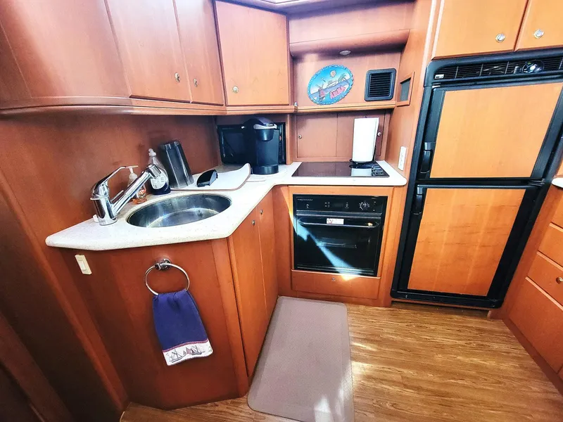 Slide: The Image of 2005 Silverton 43 Motor Yacht kitchen with wood cabinetry, sink, stove, and refrigerator. - 4