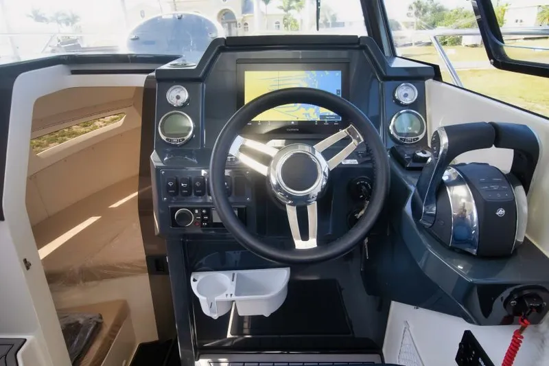 Slide: The Image of 2024 Skamander 920 Explorer Max boat cockpit with steering wheel and navigation system. - 16