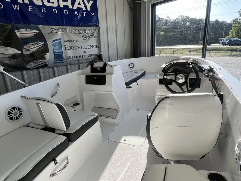 Slide: The Image of 2025 Stingray 172SC boat interior with white seating and steering wheel in showroom. - 7