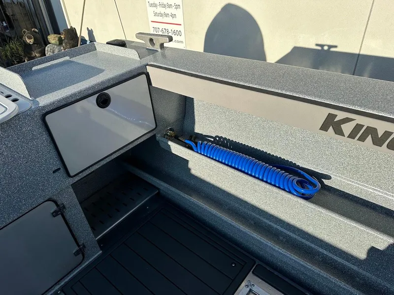 Slide: The Image of 2025 KingFisher 2625 Coastal Express boat interior with storage and coiled blue hose. - 21