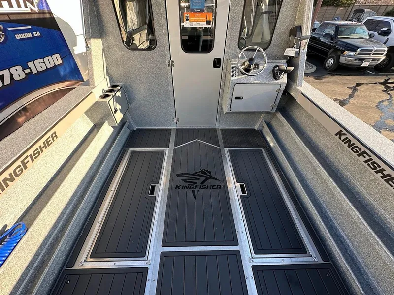 Slide: The Image of Interior of 2025 KingFisher 2625 Coastal Express boat, featuring steering console and branded flooring. - 23