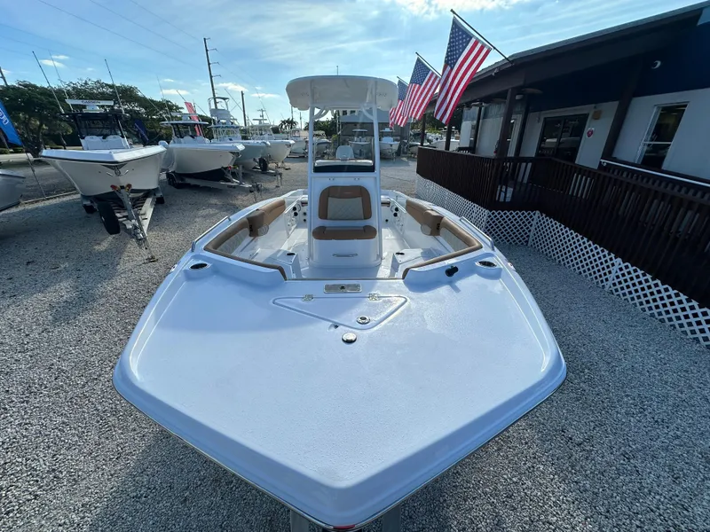 Slide: The Image of 2025 NauticStar 231 Hybrid boat displayed outdoors with American flags. - 12