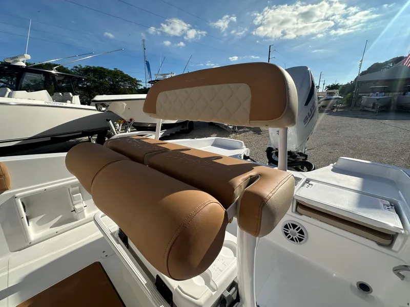 Slide: The Image of 2025 NauticStar 231 Hybrid boat seating with tan upholstery under sunny skies. - 23