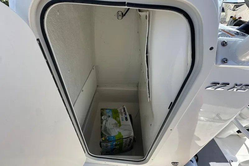 Slide: The Image of Open storage compartment on 2024 NauticStar 22XS boat, showing interior space and stored items. - 11