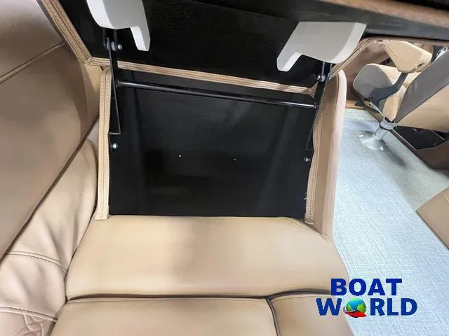 Slide: The Image of 2025 Tahoe LTZ 2385 Quad Lounge interior storage compartment, beige seating, Boat World logo. - 18