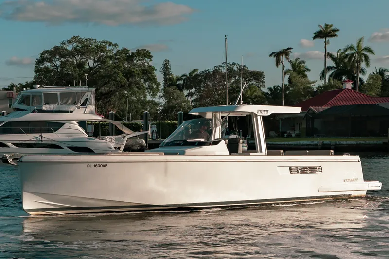 Slide: The Image of 2022 Fjord 38 Open boat cruising on a sunny day, surrounded by palm trees. - 12