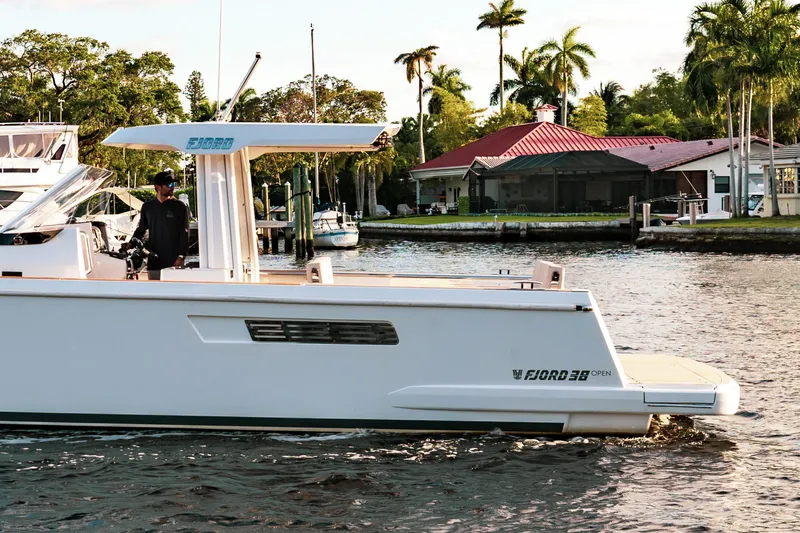 Slide: The Image of 2022 Fjord 38 Open boat cruising on a scenic waterway with lush greenery. - 15