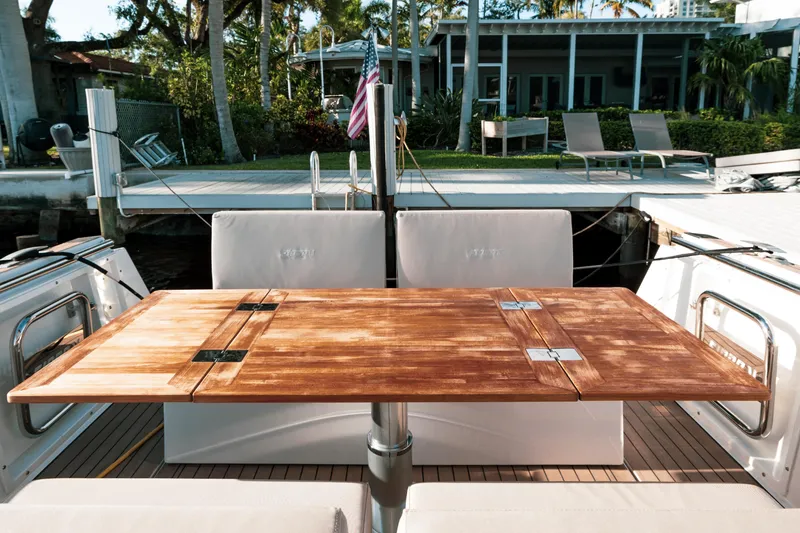 Slide: The Image of Fjord 38 Open 2022 boat with wooden table and seating area, docked near a modern house. - 25