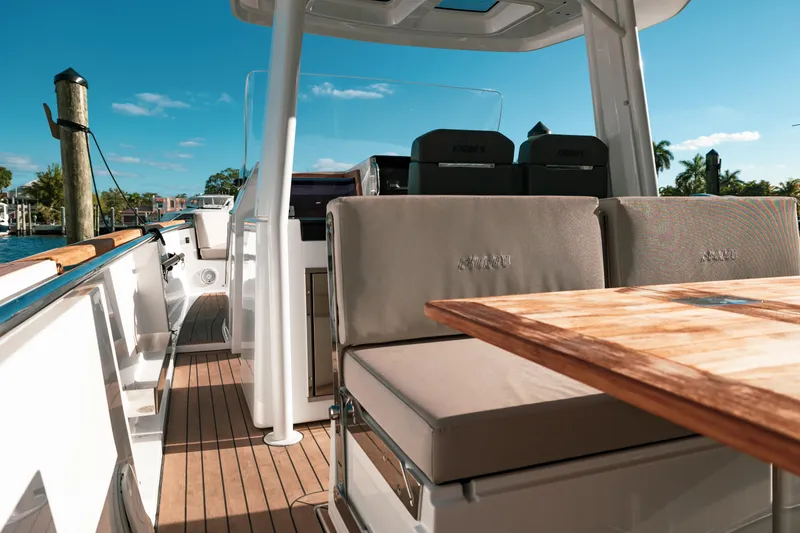 Slide: The Image of 2022 Fjord 38 Open boat interior with seating and wooden table, docked under clear blue sky. - 28