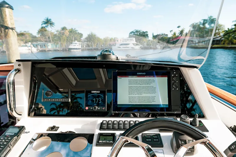 Slide: The Image of 2022 Fjord 38 Open yacht dashboard with navigation screens and steering wheel, cruising on a sunny day. - 42