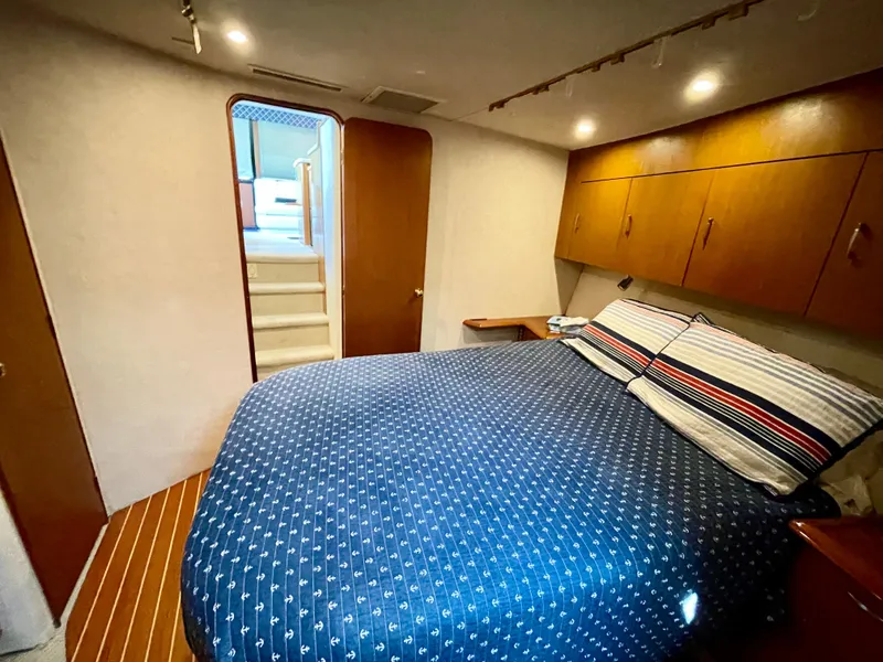 Slide: The Image of Cozy bedroom in 2000 Ocean Yachts 43 Super Sport with blue bedding and wooden cabinets. - 10