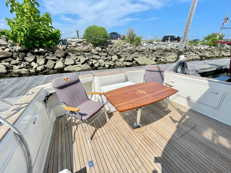 Slide: The Image of 2000 Ocean Yachts 43 Super Sport deck with chairs and table, docked by rocky shoreline. - 30