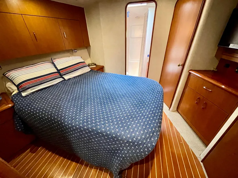 Slide: The Image of Cozy bedroom in 2000 Ocean Yachts 43 Super Sport with wooden cabinetry and blue bedding. - 9