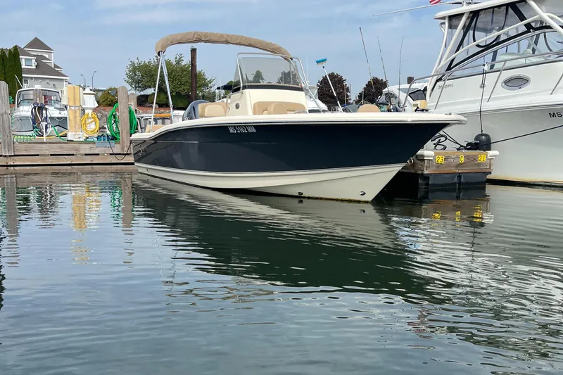 Slide: The Image of 2024 Scout 195 Sportfish boat docked in marina, calm water reflection. - 0