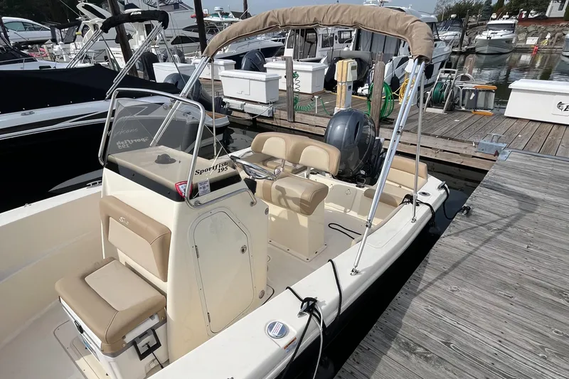 Slide: The Image of 2024 Scout 195 Sportfish boat docked, featuring beige seating and a sleek design. - 19