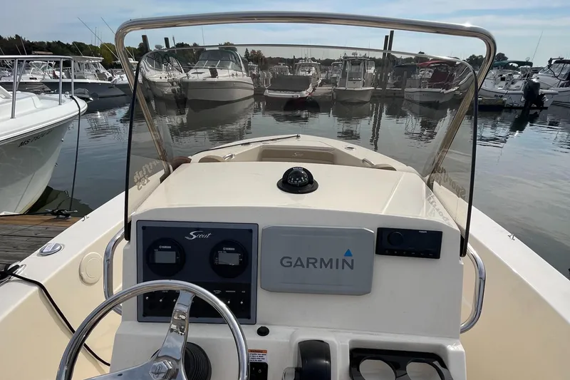 Slide: The Image of 2024 Scout 195 Sportfish boat dashboard with Garmin navigation, docked in marina. - 22
