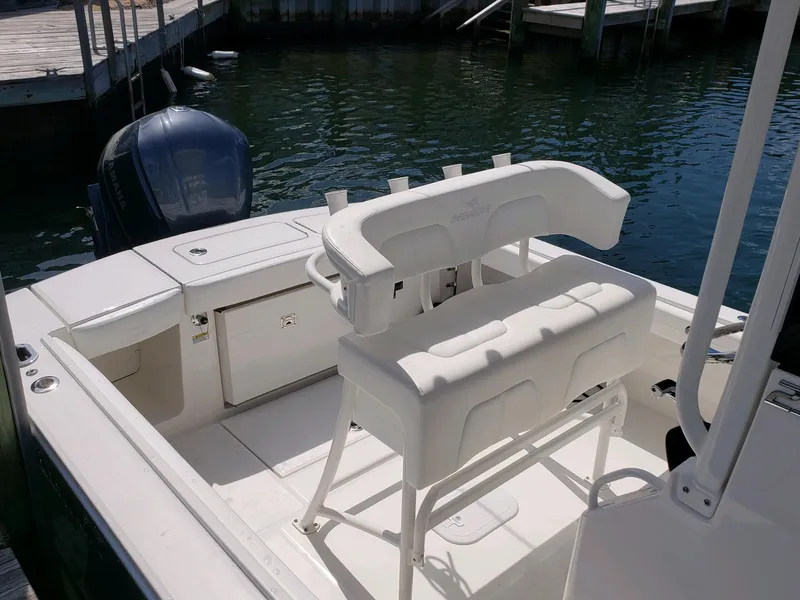 Slide: The Image of 2020 Regulator 23 Forward Seating boat with white seating and outboard motor in marina. - 13