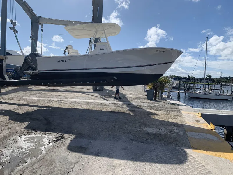 Slide: The Image of 2017 Regulator 23 Forward Seating boat lifted at marina under clear sky. - 8