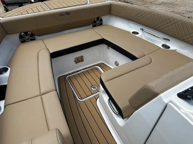 Slide: The Image of 2025 Sea Ray SDX 270 boat interior with tan seating and wood-style flooring. - 2