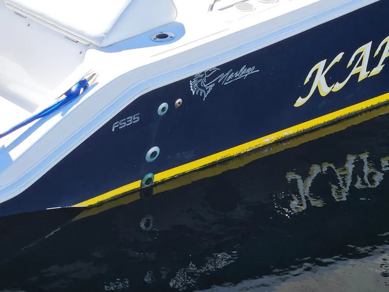Slide: The Image of 2004 Marlago FS35 boat, blue and yellow detailing, docked on water. - 6