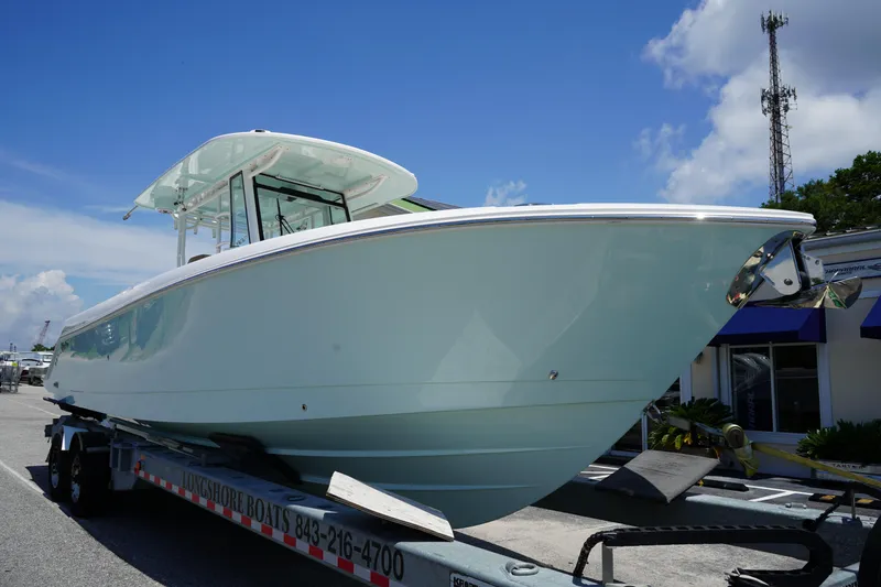 Slide: The Image of 2025 Edgewater 340CC boat on trailer under clear blue sky. - 2