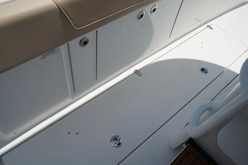 Slide: The Image of Storage compartment in 2025 Edgewater 340CC boat, featuring rod holders and a fire extinguisher. - 44