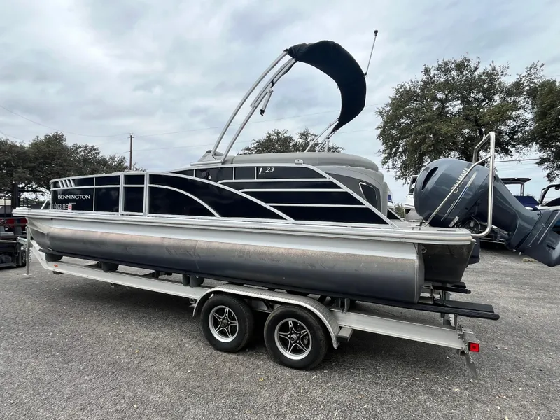 Slide: The Image of 2022 Bennington 23LTFB pontoon boat on trailer, black and silver design. - 2