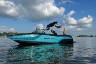 Slide: The Image of 2024 MasterCraft NXT22 boat on a lake under a blue sky with clouds. - 0