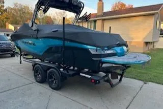 Slide: The Image of 2024 MasterCraft NXT22 boat on trailer, covered, parked in driveway. - 1