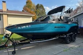 Slide: The Image of 2024 MasterCraft NXT22 boat on trailer in residential driveway. - 2