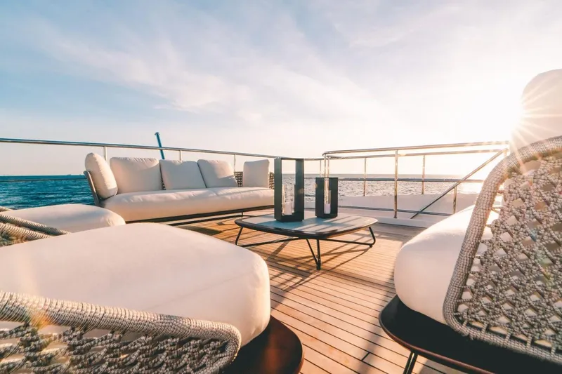 Slide: The Image of Luxurious Benetti Delfino 95 yacht deck with elegant seating, ocean view, and sunset ambiance. - 19