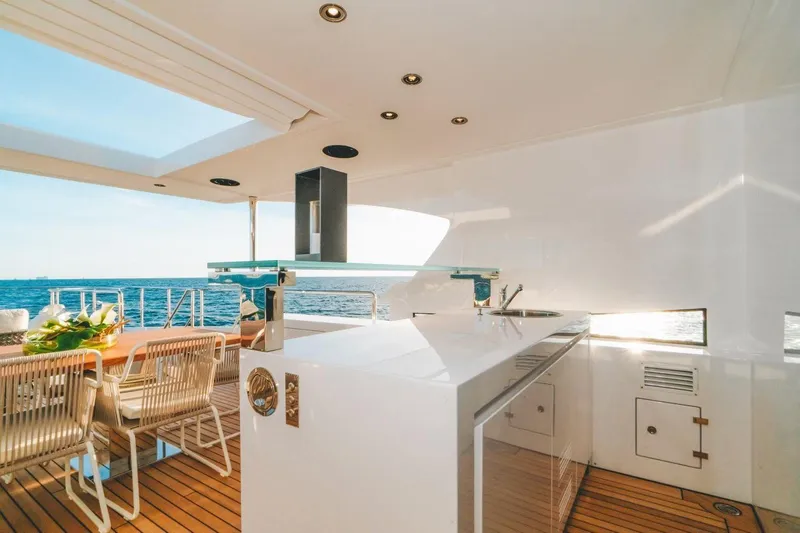 Slide: The Image of Luxurious Benetti Delfino 95 yacht deck with modern outdoor kitchen, dining area, and ocean view. - 22