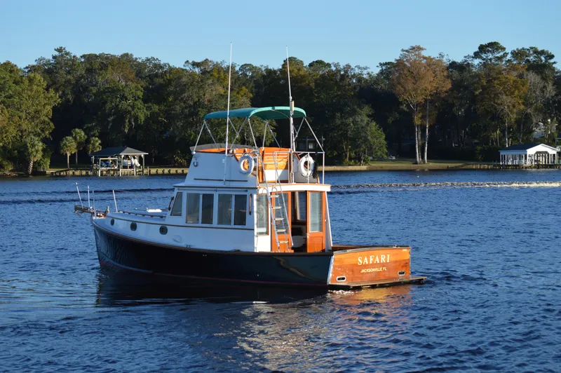 Slide: The Image of 1990 Stanley Downeast Lobster Boat cruising on a serene lake with lush forest backdrop. - 2