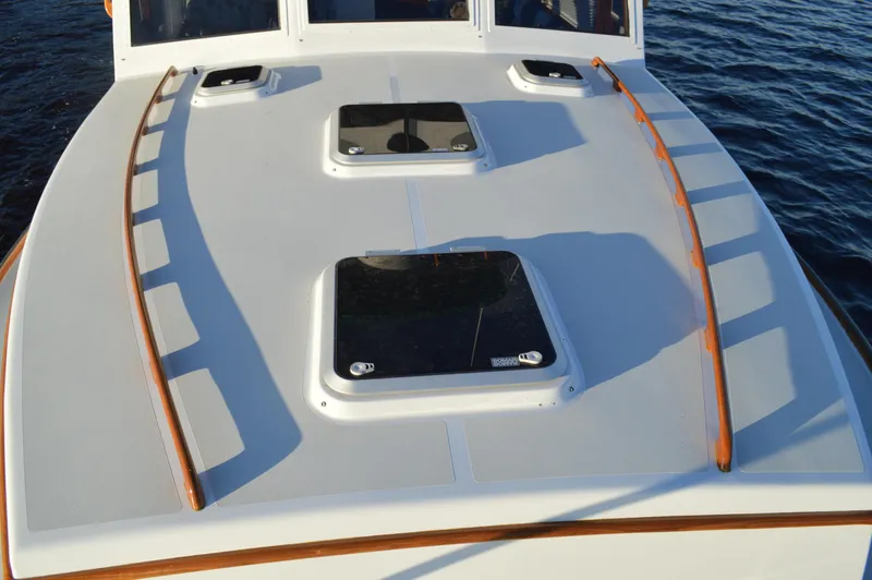 Slide: The Image of 1990 Stanley Downeast Lobster Boat deck with hatches and wooden railings, on calm water. - 7