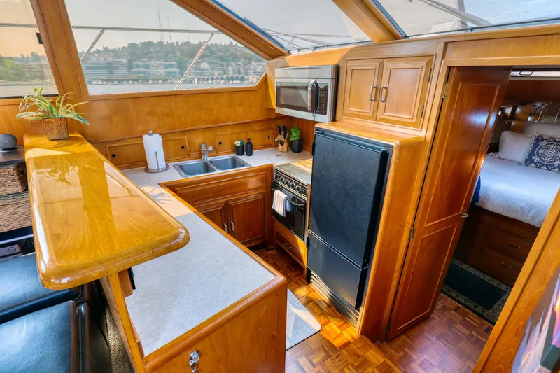 Slide: The Image of 1987 Ocean Alexander Motoryacht kitchen with wood cabinetry, modern appliances, and cozy bedroom view. - 11