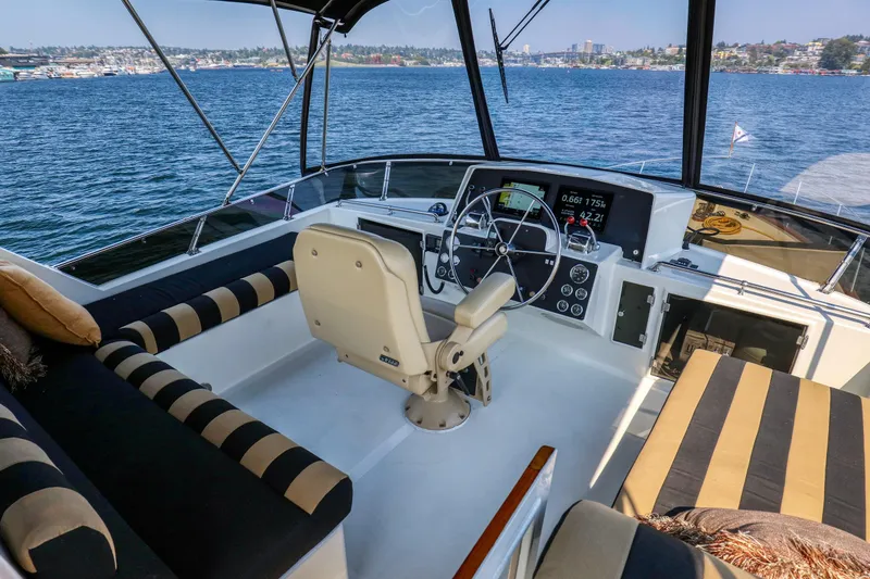 Slide: The Image of 1987 Ocean Alexander Motoryacht helm with striped seating, overlooking scenic waterfront. - 4