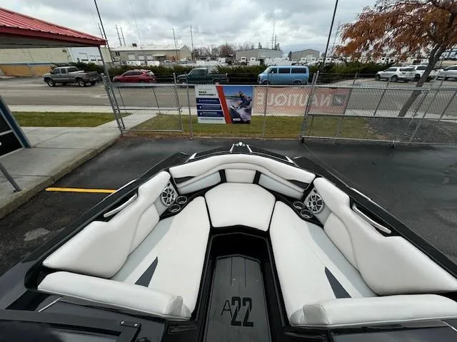 Slide: The Image of 2018 Axis A22 boat interior with white seating, parked outdoors. - 14