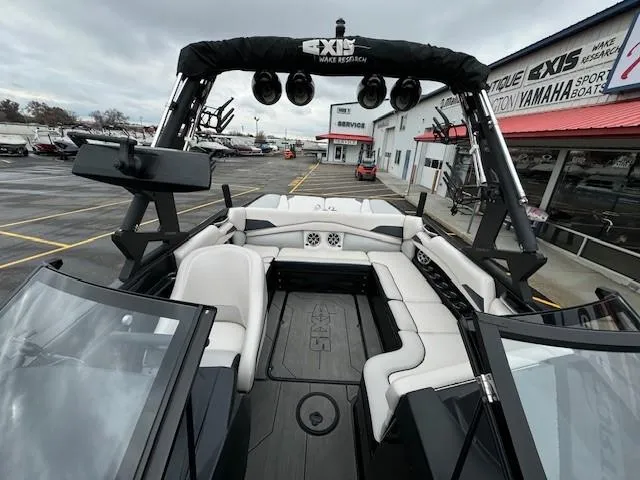 Slide: The Image of 2018 Axis A22 boat interior with seating and speakers, parked at a dealership. - 15