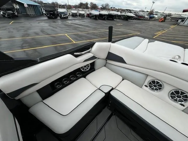 Slide: The Image of 2018 Axis A22 boat interior with white seating and speaker system in a parking lot. - 17