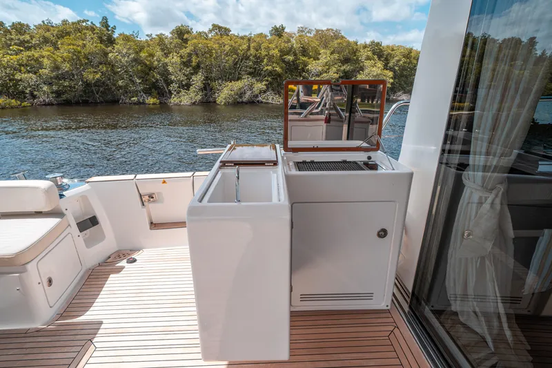 Slide: The Image of Azimut Magellano 53 yacht deck with outdoor kitchen, 2018 model, near lush shoreline. - 24