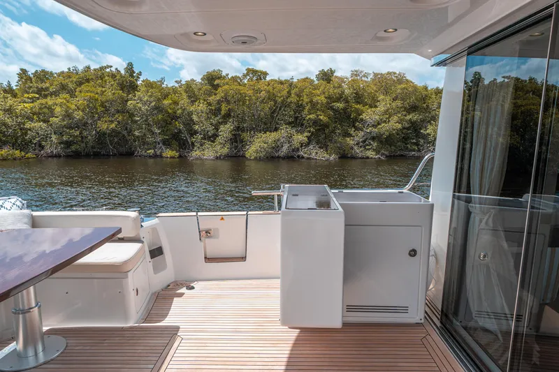 Slide: The Image of Azimut Magellano 53 yacht deck with seating, 2018 model, near lush greenery. - 28