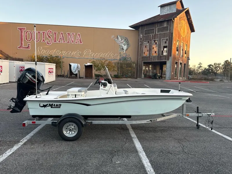 Slide: The Image of 2025 Mako Pro Skiff 15 CC boat on trailer in parking lot, Louisiana backdrop. - 2